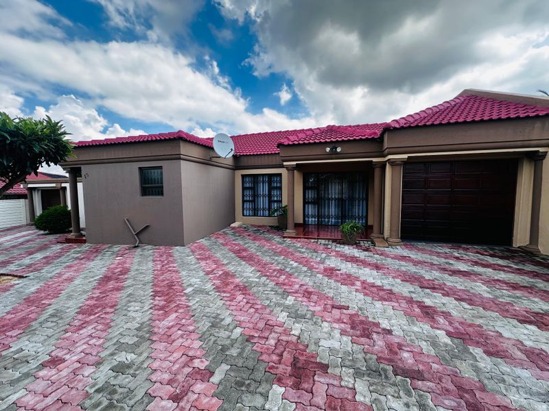 Front elevation of a residential house featuring a paved driveway, integrated garage, and security-fitted windows and entrance.