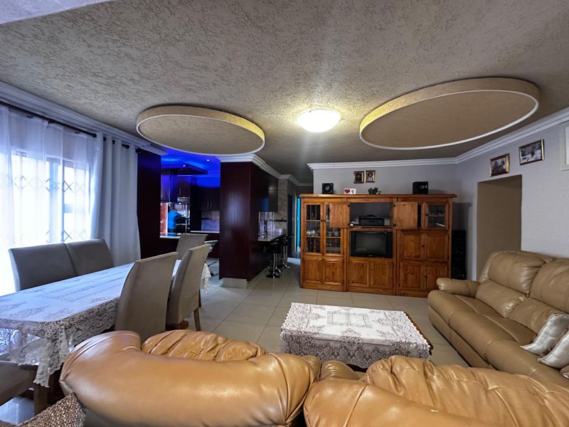 Spacious open-plan living and dining area featuring unique circular ceiling details, tiled flooring, and an integrated kitchen with a breakfast bar.