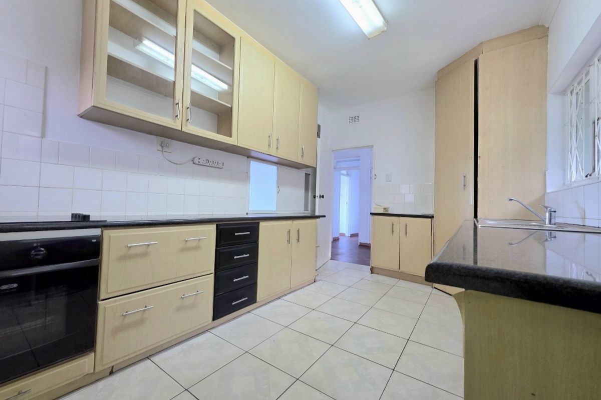 A functional kitchen featuring light-toned built-in cabinetry, granite countertops, tiled backsplash, and ceramic flooring, offering a clean and practical workspace.