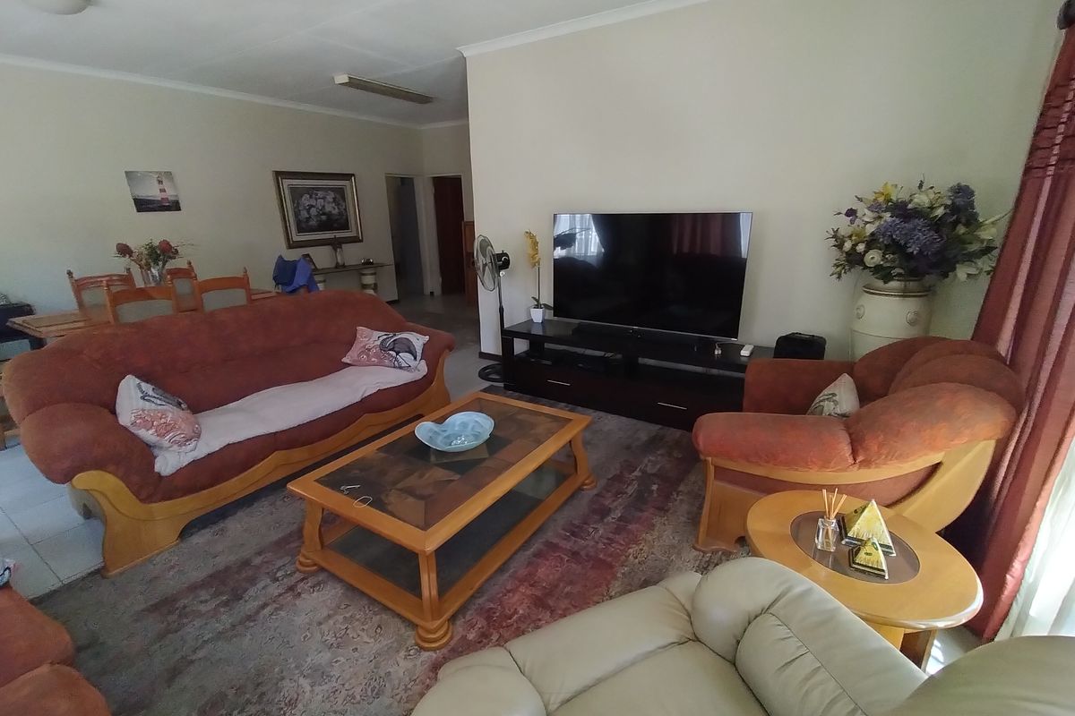 A spacious living room featuring tiled flooring and classic cove cornicing, providing a comfortable and functional area for relaxation.