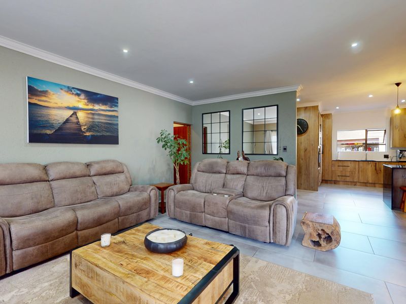 Spacious open-plan living area featuring tiled floors, recessed lighting, and a modern kitchen with wood-finish cabinetry and a central island.