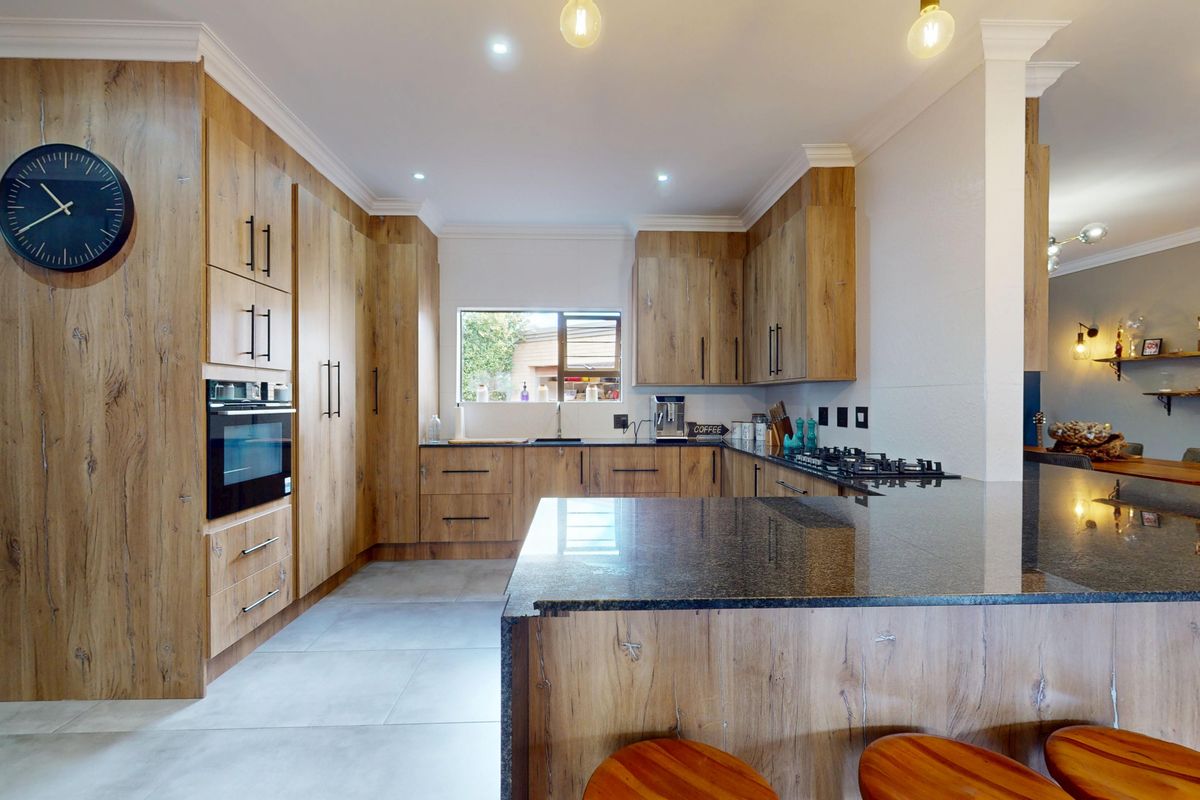 Modern kitchen featuring wood-look cabinetry, granite countertops, built-in oven, and gas hob, offering a functional and stylish workspace.