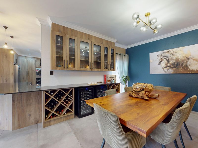 Open plan dining area featuring custom built-in cabinetry, integrated wine storage, stone countertops, and modern lighting fixtures with a feature wall.