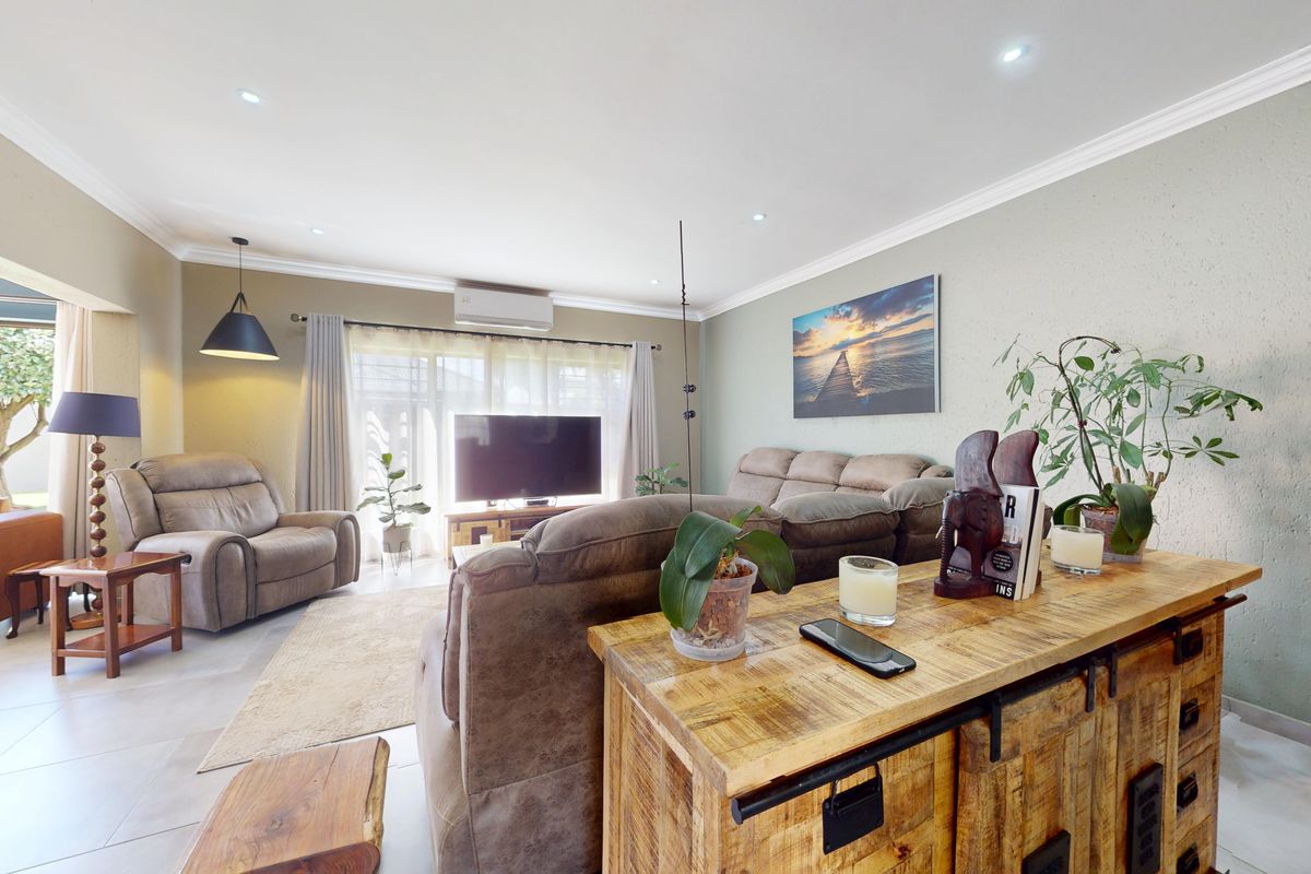 Spacious living room featuring tiled flooring, recessed downlights, and a split-system air conditioner, with direct access to an outdoor patio area.