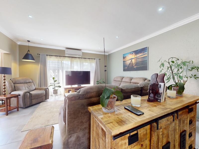 Spacious living room featuring tiled flooring, recessed downlights, and a split-system air conditioner, with direct access to an outdoor patio area.