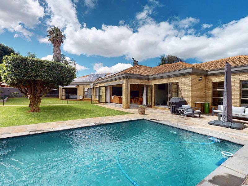 A well-maintained rear exterior featuring a swimming pool, paved patio area, and brick facade with stacking doors leading into the home.