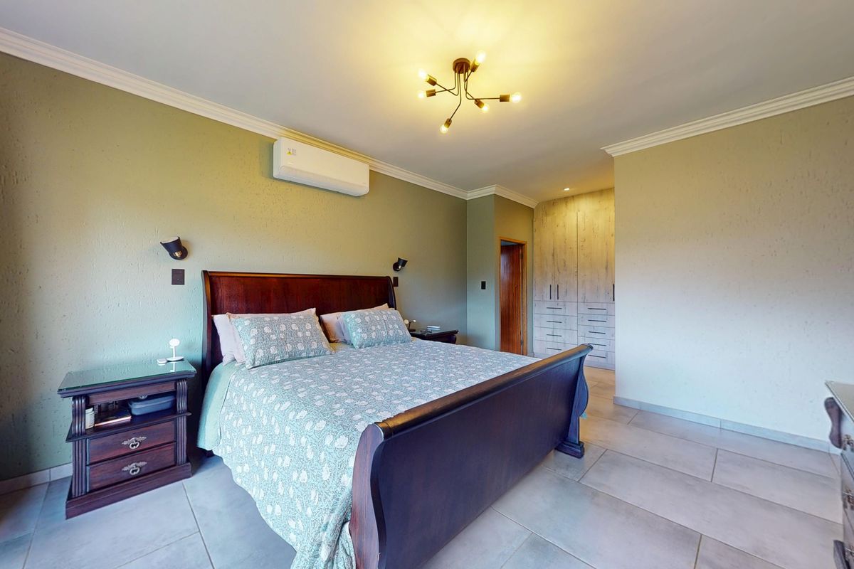 Spacious bedroom featuring tiled flooring, built-in cupboards, and a wall-mounted air conditioning unit.