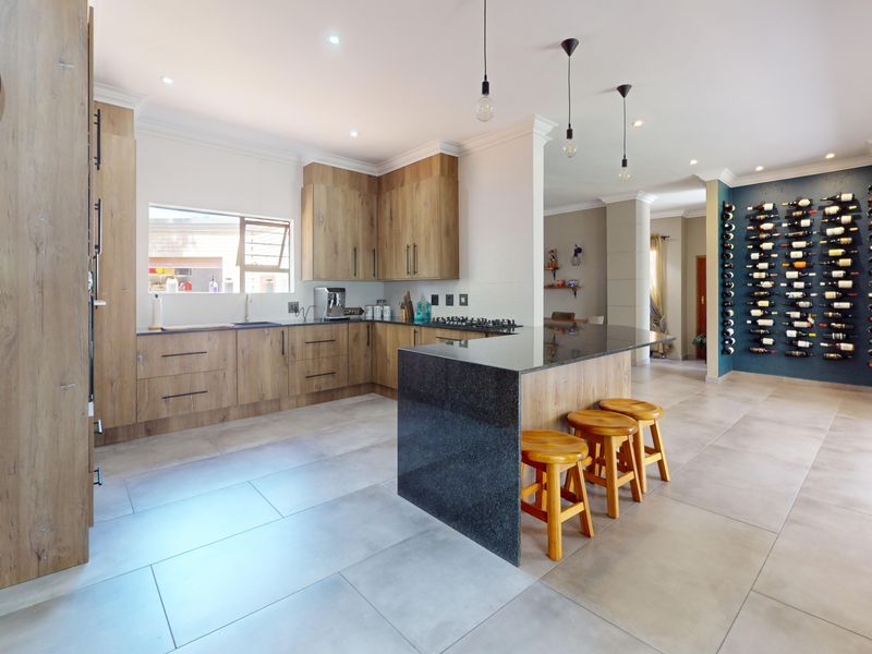 Modern open-plan kitchen featuring wood-look cabinetry, a granite island with breakfast bar, and a dedicated feature wall with built-in wine storage.