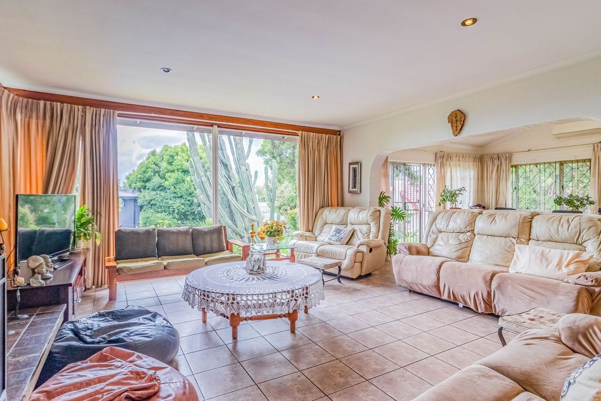 Spacious living room featuring a stone fireplace, tiled flooring, and large sliding glass doors that provide ample natural light and garden views.