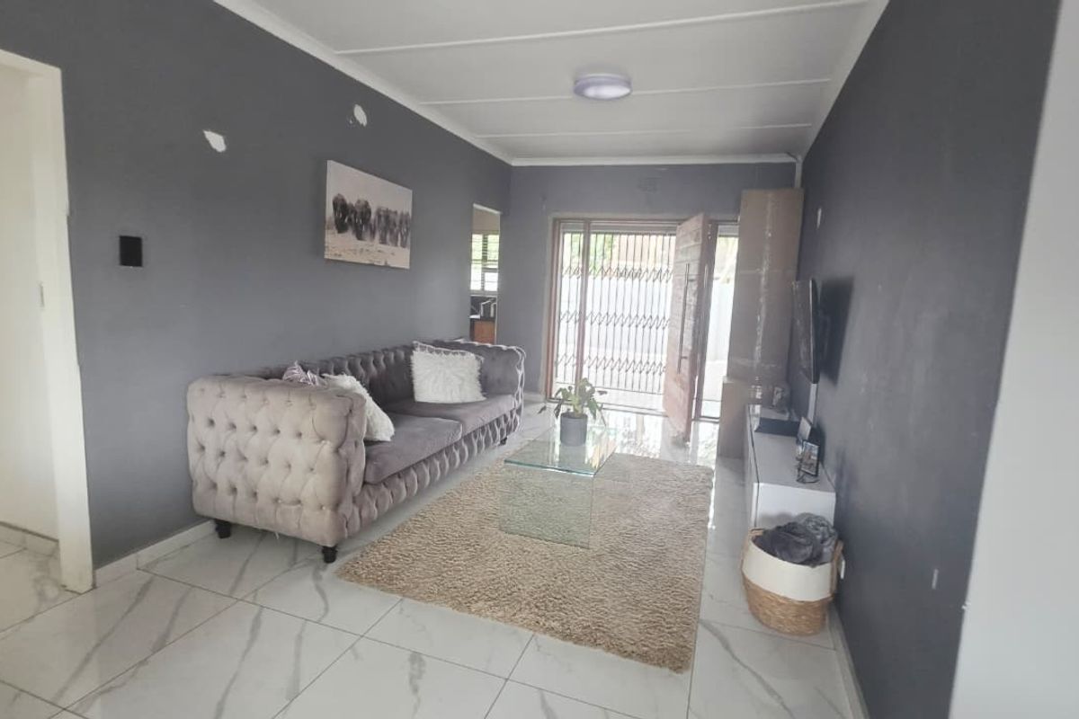 A living room featuring tiled flooring and access to the exterior via a security gate and sliding door.