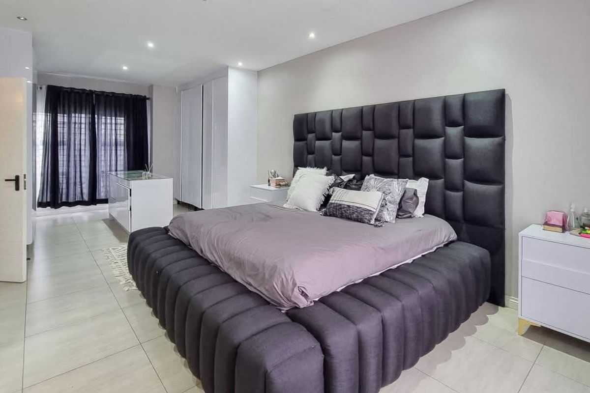 Spacious bedroom featuring neutral tiled flooring, recessed downlighting, and ample built-in cupboard storage.