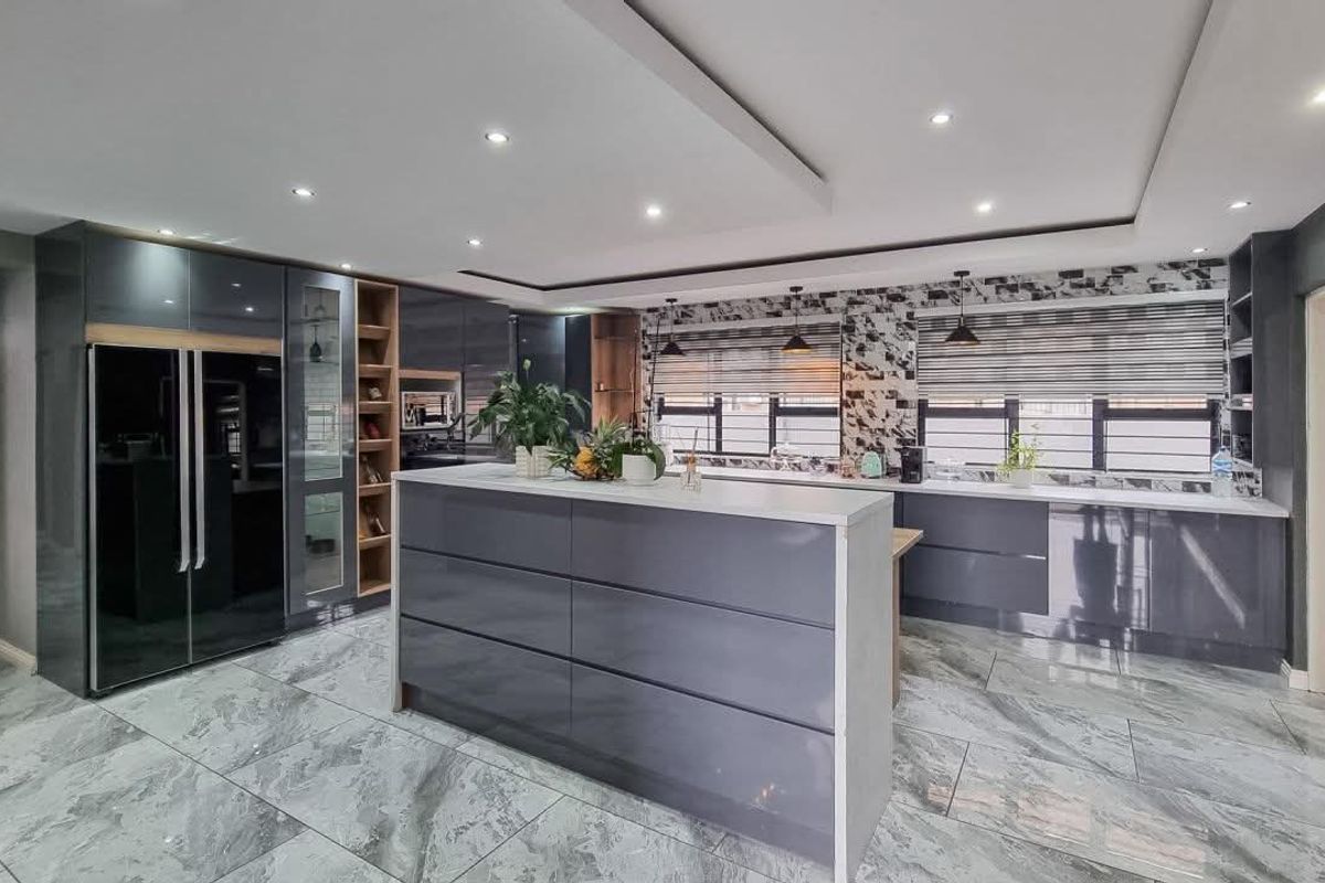 Modern kitchen featuring high-gloss cabinetry, a central island, stone tile flooring, and recessed lighting with a contemporary tiled backsplash.