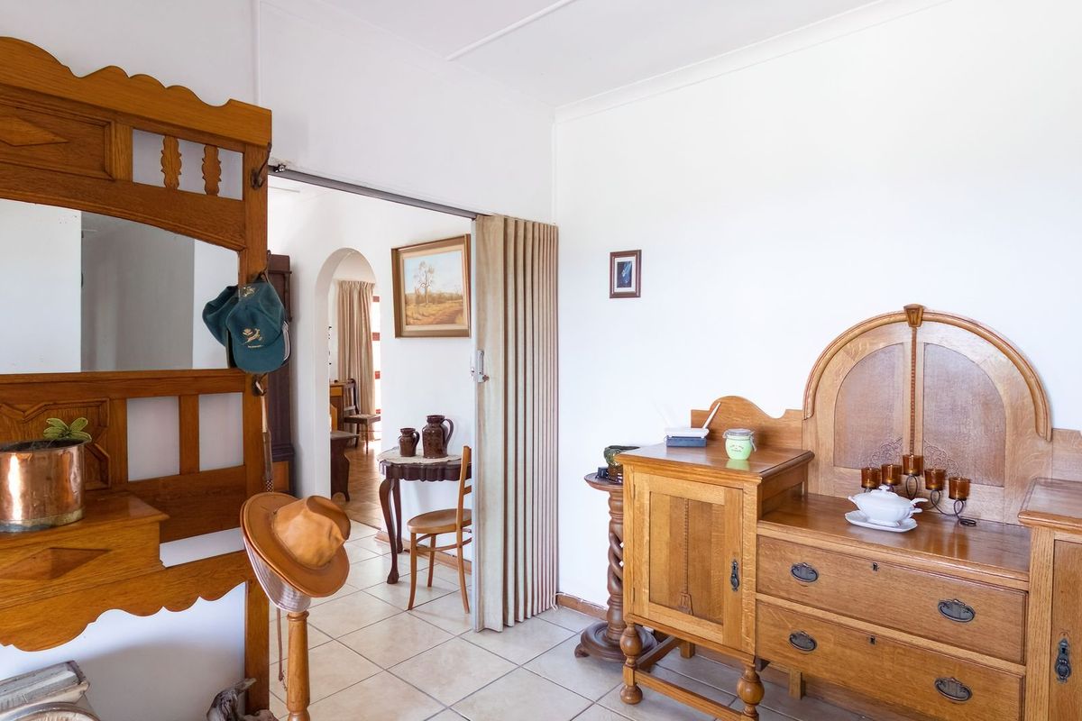 A view of an interior living space featuring tiled flooring, a folding room divider, and an arched doorway leading to an adjacent room.