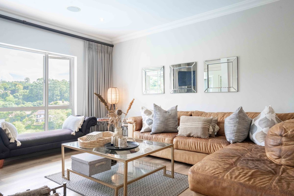 A bright and inviting living room featuring large windows with scenic views, recessed ceiling lighting, and neutral finishes.