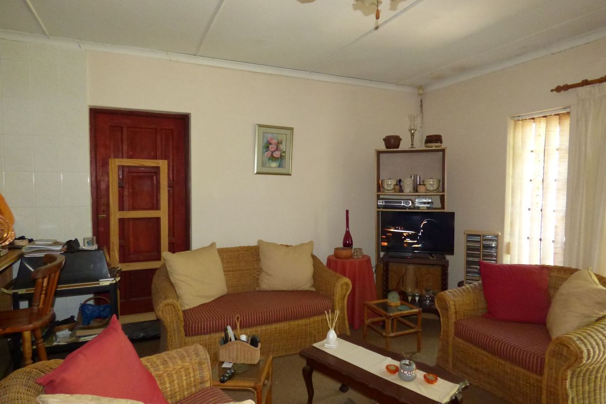 A living room featuring a ceiling fan and a tiled fireplace surround, requiring cosmetic updates to modernize the space.