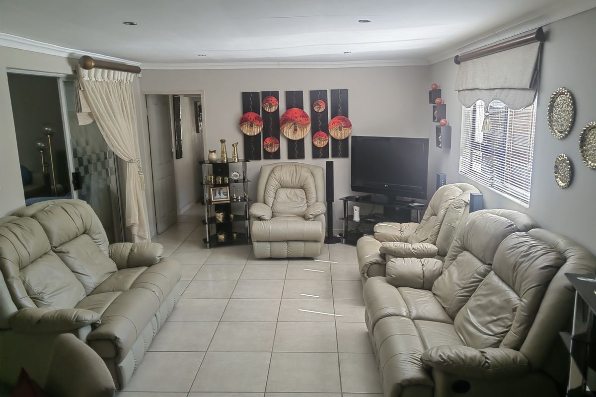 A comfortable living room featuring neutral tiled flooring, recessed downlighting, and a sliding glass door providing access to the exterior.
