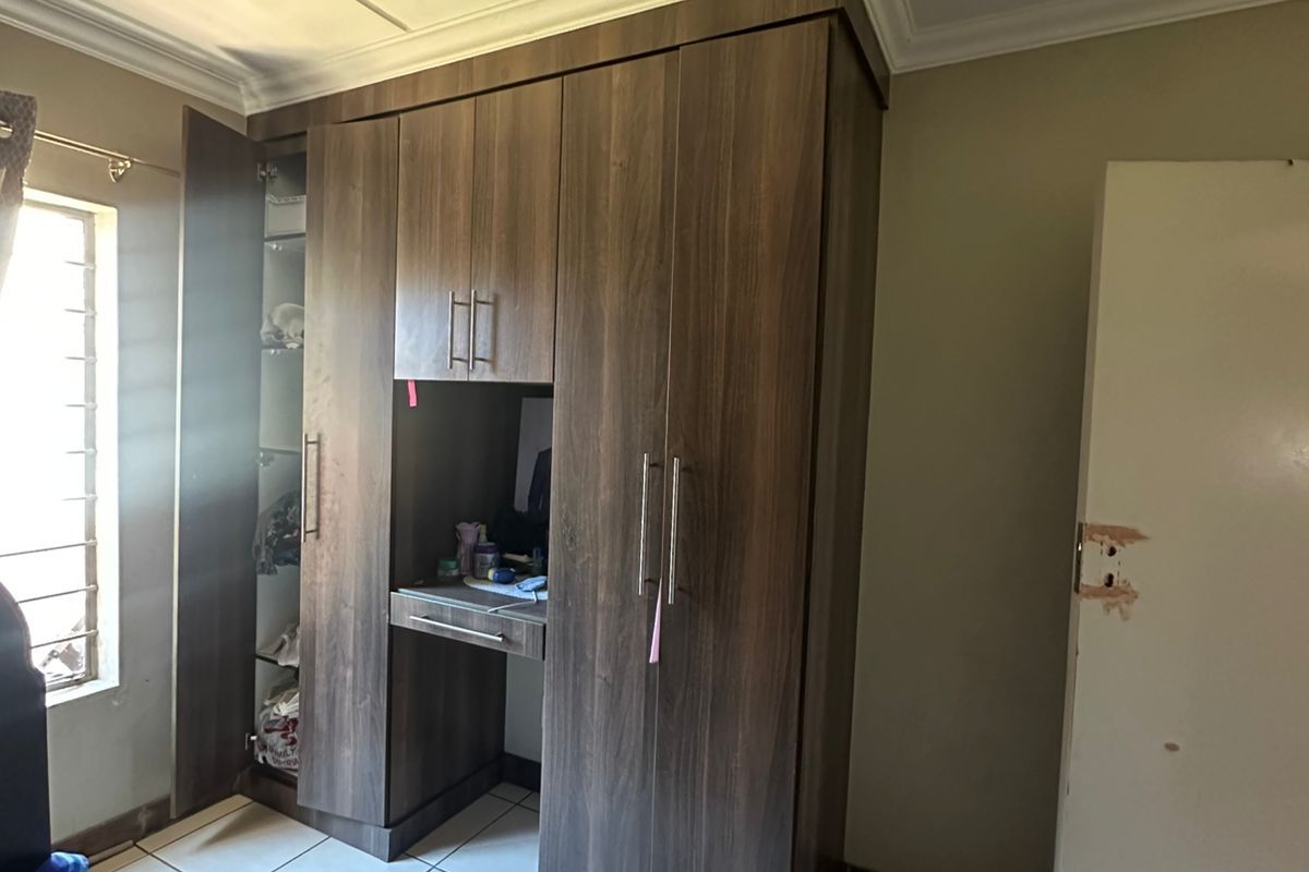 A bedroom featuring built-in dark wood cabinetry with an integrated desk unit and tiled flooring.