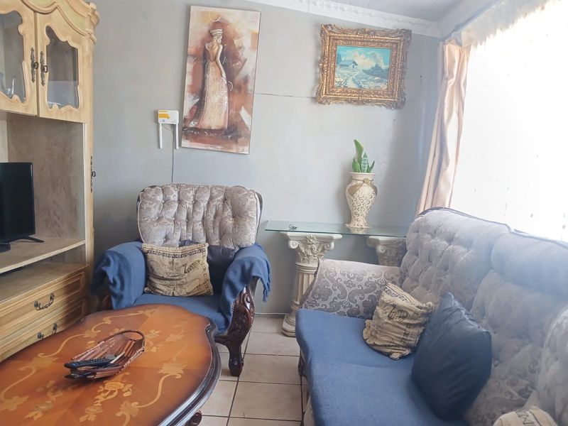 A living room area featuring tiled flooring and decorative ceiling cornicing, currently showing signs of wear on the wall surfaces.