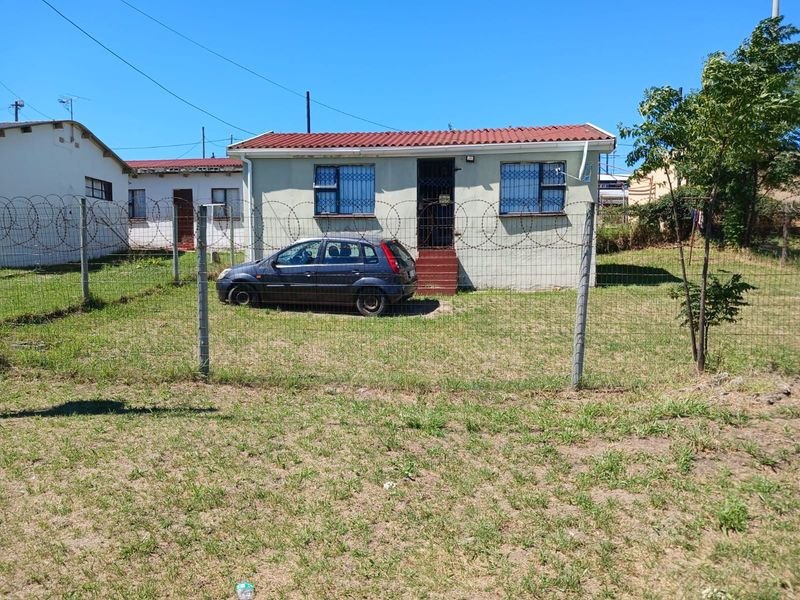 Front view of a single-story house featuring security bars on windows, razor wire perimeter fencing, and a tiled roof.