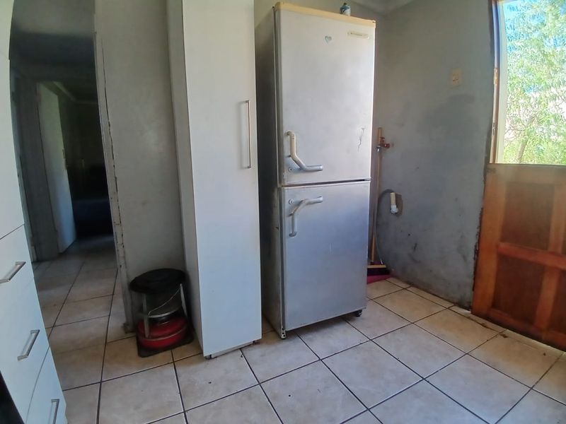 A functional laundry area featuring tiled flooring and direct access to the exterior, providing a practical space for utility needs.