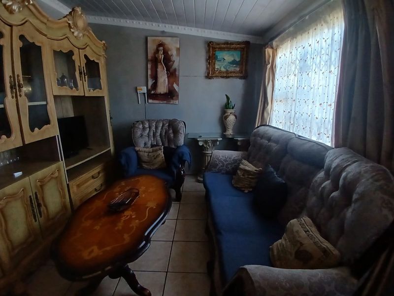 A living room featuring tiled flooring and a tongue and groove ceiling, currently furnished with traditional pieces.