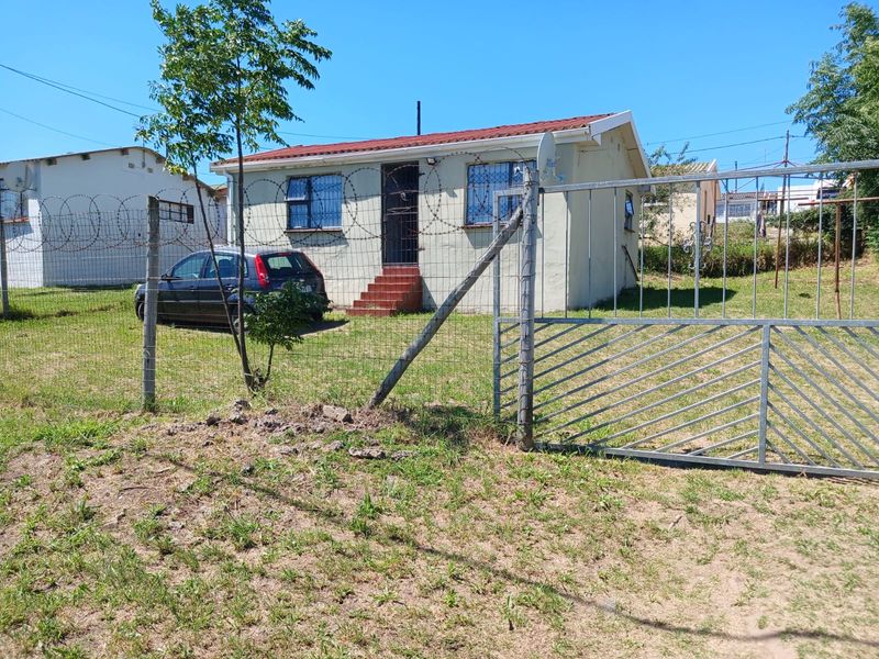 Front view of a detached house featuring a metal security gate, razor wire perimeter fencing, and security bars on windows.