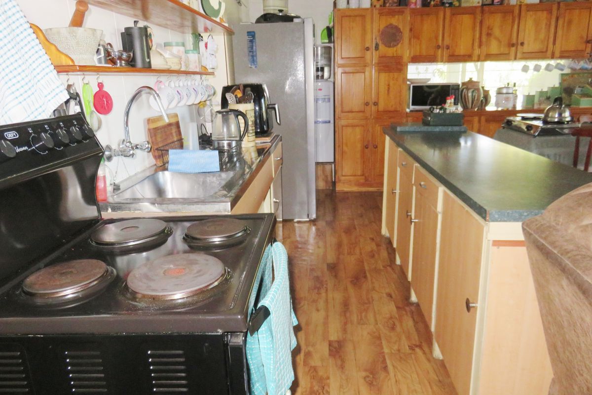 A functional kitchen featuring timber cabinetry, laminate countertops, a freestanding electric stove, and wood-look flooring.
