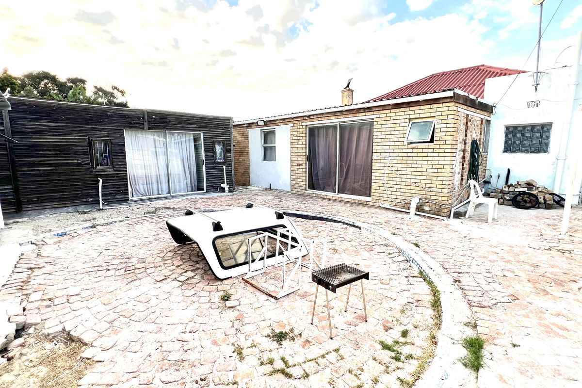 Rear courtyard area featuring paved flooring, sliding glass doors, and a mix of brick and timber-clad exterior walls.
