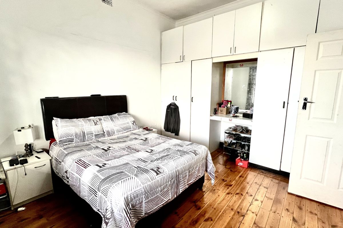 A bedroom featuring built-in floor-to-ceiling cabinetry with an integrated vanity area and original timber flooring.