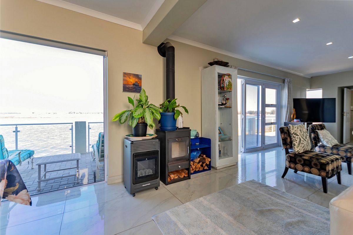 Spacious living area featuring polished tiled floors, a wood-burning fireplace, and large sliding glass doors providing seamless access to the outdoor patio and water views.