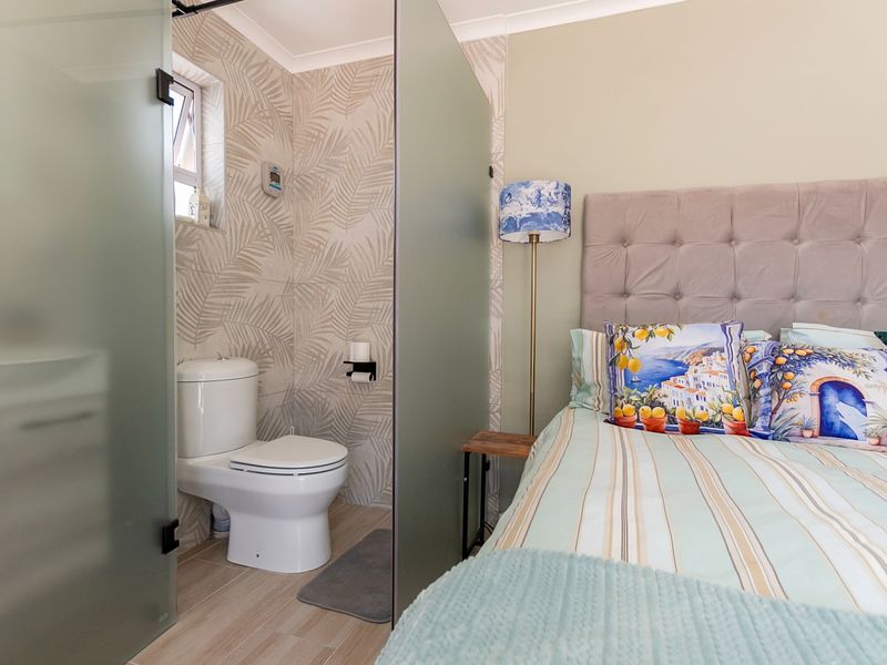 Bedroom featuring an integrated en-suite toilet area separated by a modern frosted glass partition, finished with patterned wall tiling and neutral flooring.