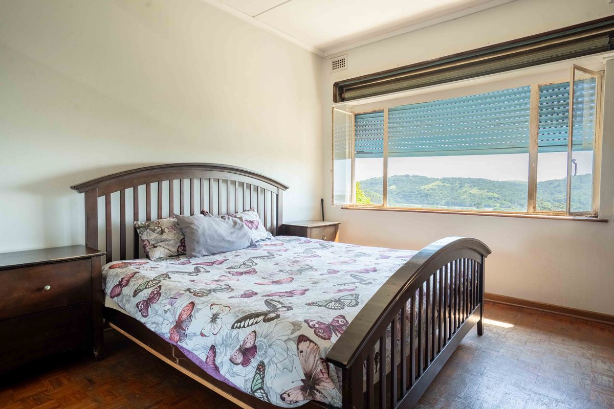 A bedroom featuring parquet flooring and a large window with an integrated external roller shutter, offering scenic hillside views.