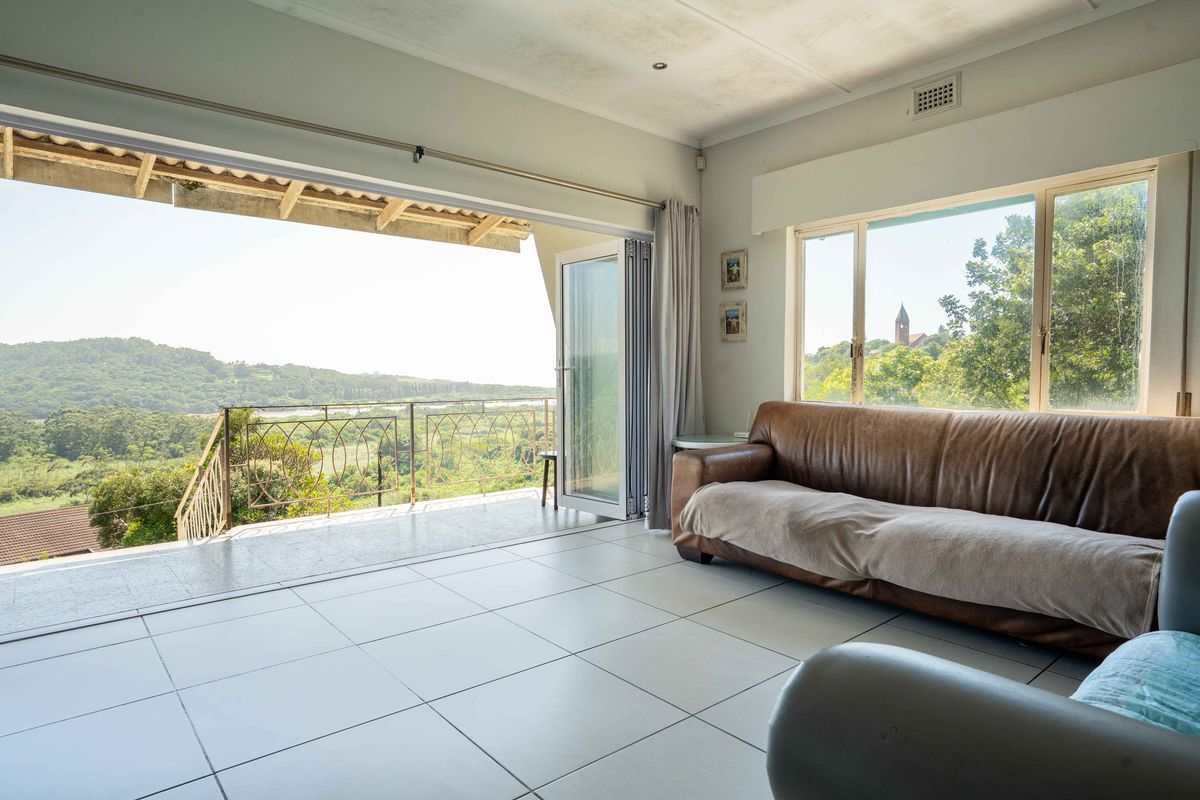 Spacious living area featuring large windows and bi-fold doors opening onto a covered balcony with scenic landscape views.