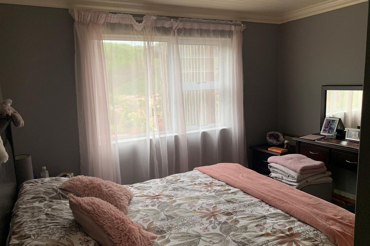 A cozy bedroom featuring a beadboard ceiling, crown molding, and a sliding window that allows for natural light.