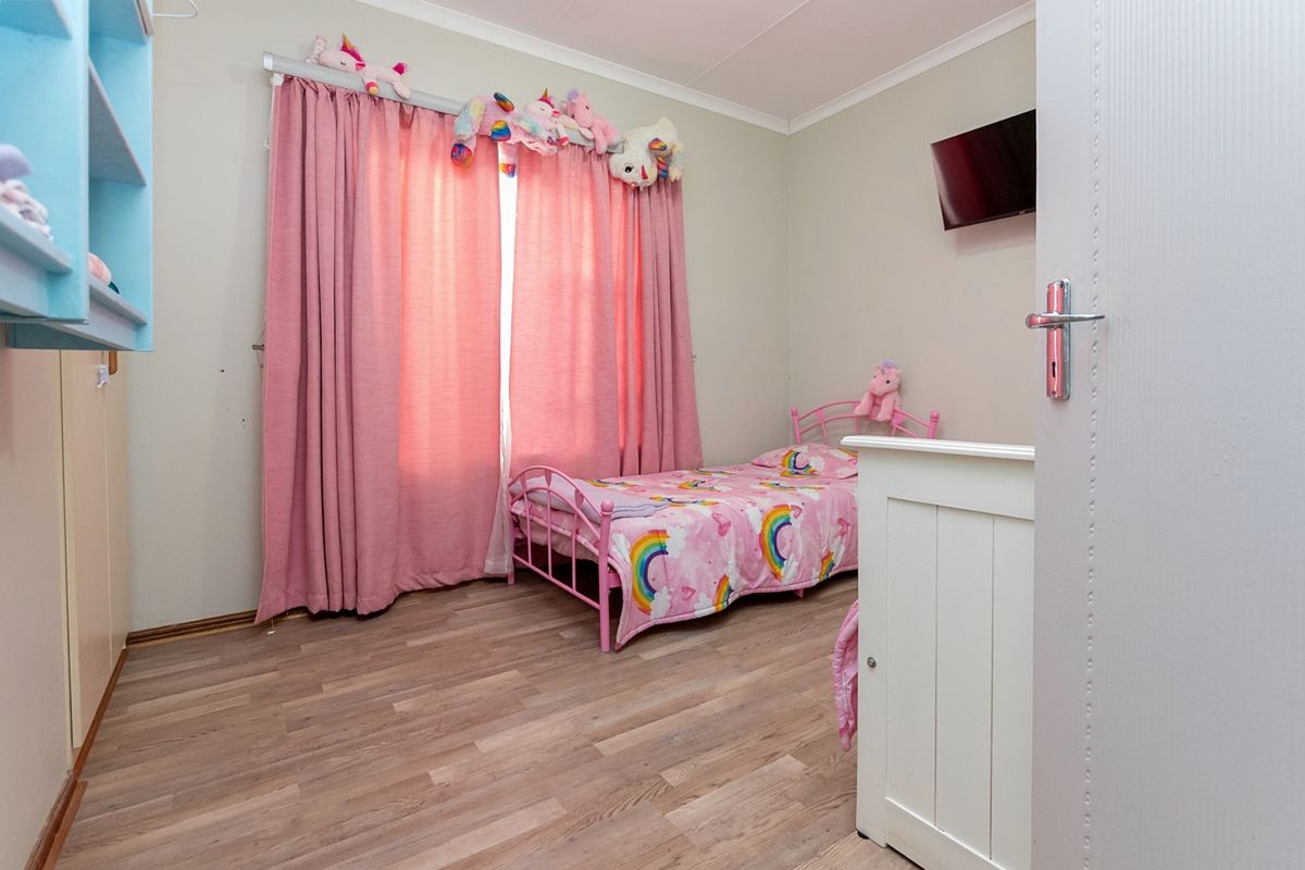 A bedroom featuring light-toned laminate flooring, neutral wall paint, and a coved ceiling, providing a functional and well-lit living space.