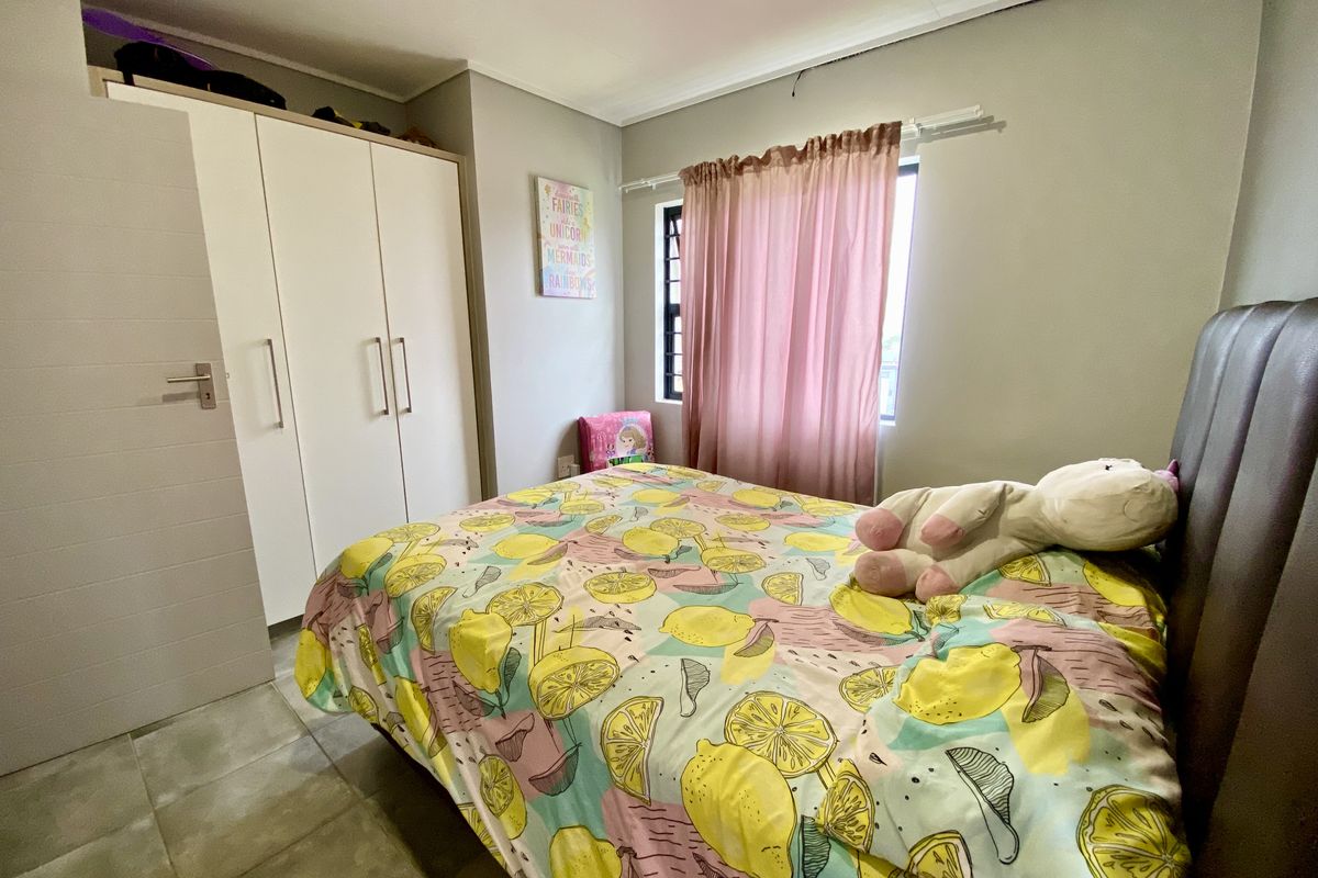 A functional bedroom featuring tiled flooring, a built-in wardrobe, and a window with natural light.
