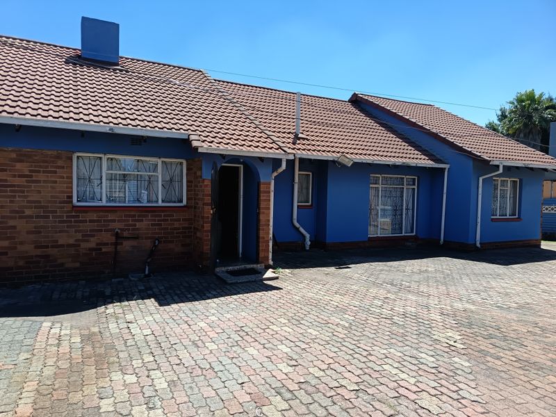 Front elevation of a single-story house featuring a tiled roof, brick and painted exterior walls, and a paved driveway.