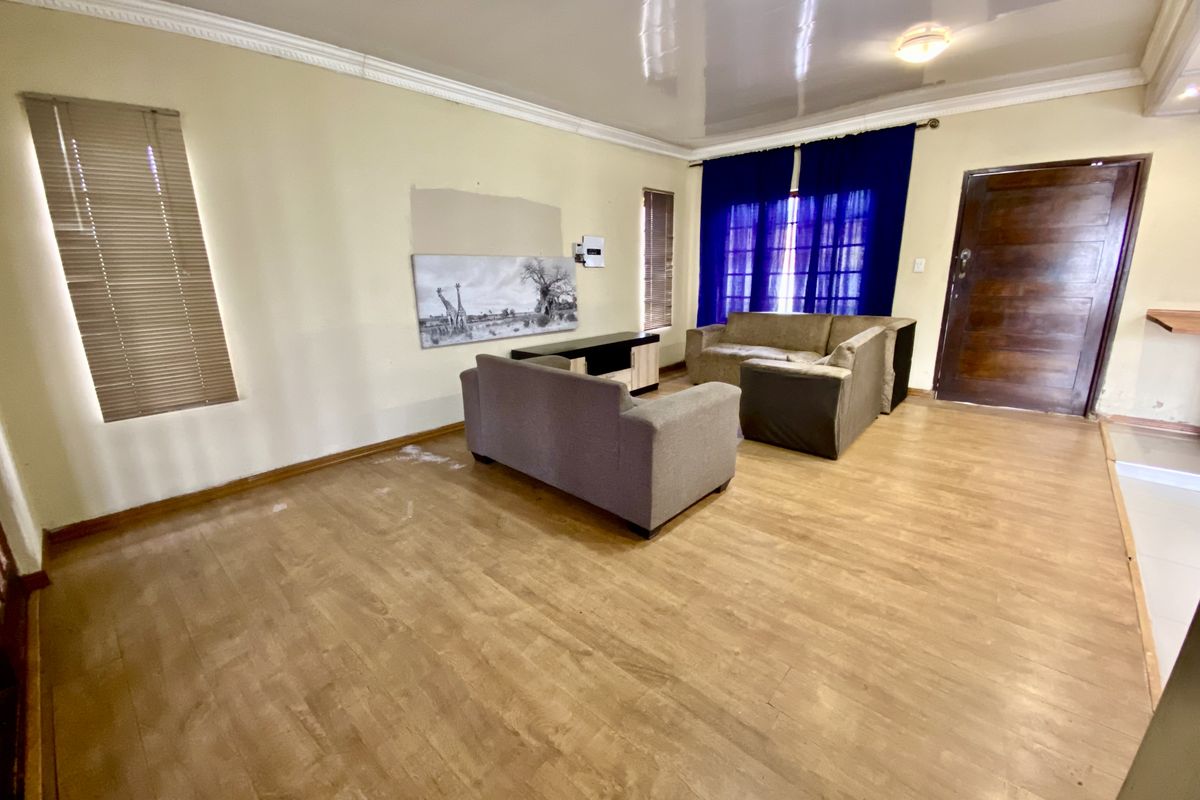 Spacious living room featuring laminate flooring, crown molding, and a glossy ceiling finish, providing a neutral base for interior design updates.
