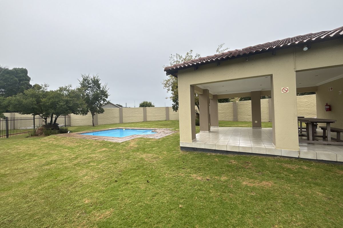 Spacious rear garden featuring a covered patio area, a swimming pool, and a secure perimeter wall, ideal for outdoor entertaining.