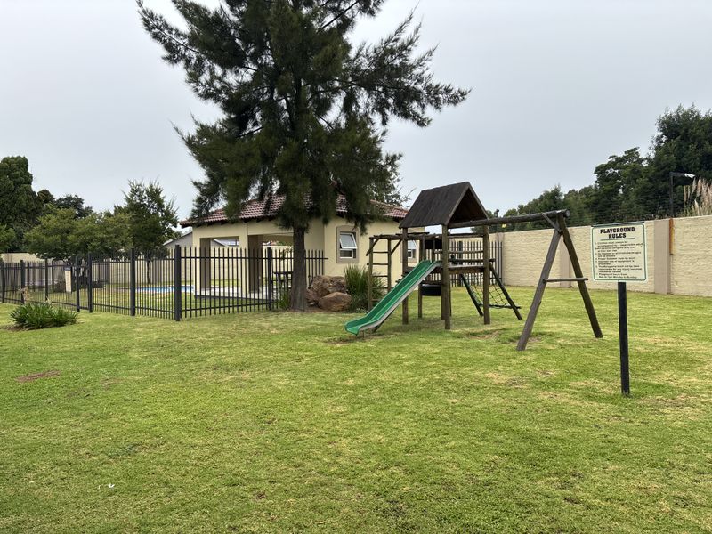 Communal estate area featuring a playground, swimming pool, and covered pavilion for resident recreation.
