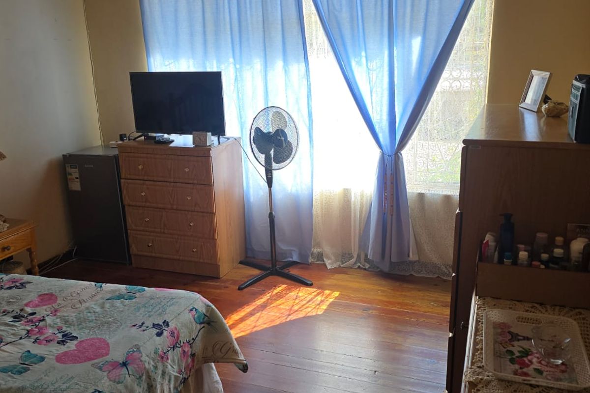 A bedroom featuring original timber flooring and natural light through a large window.