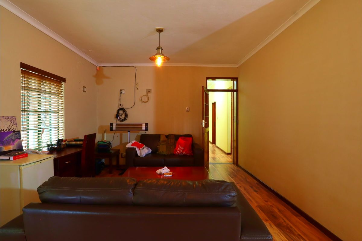 A living room featuring wooden flooring, venetian blinds, and cove cornicing, requiring minor cosmetic updates to improve the overall finish.
