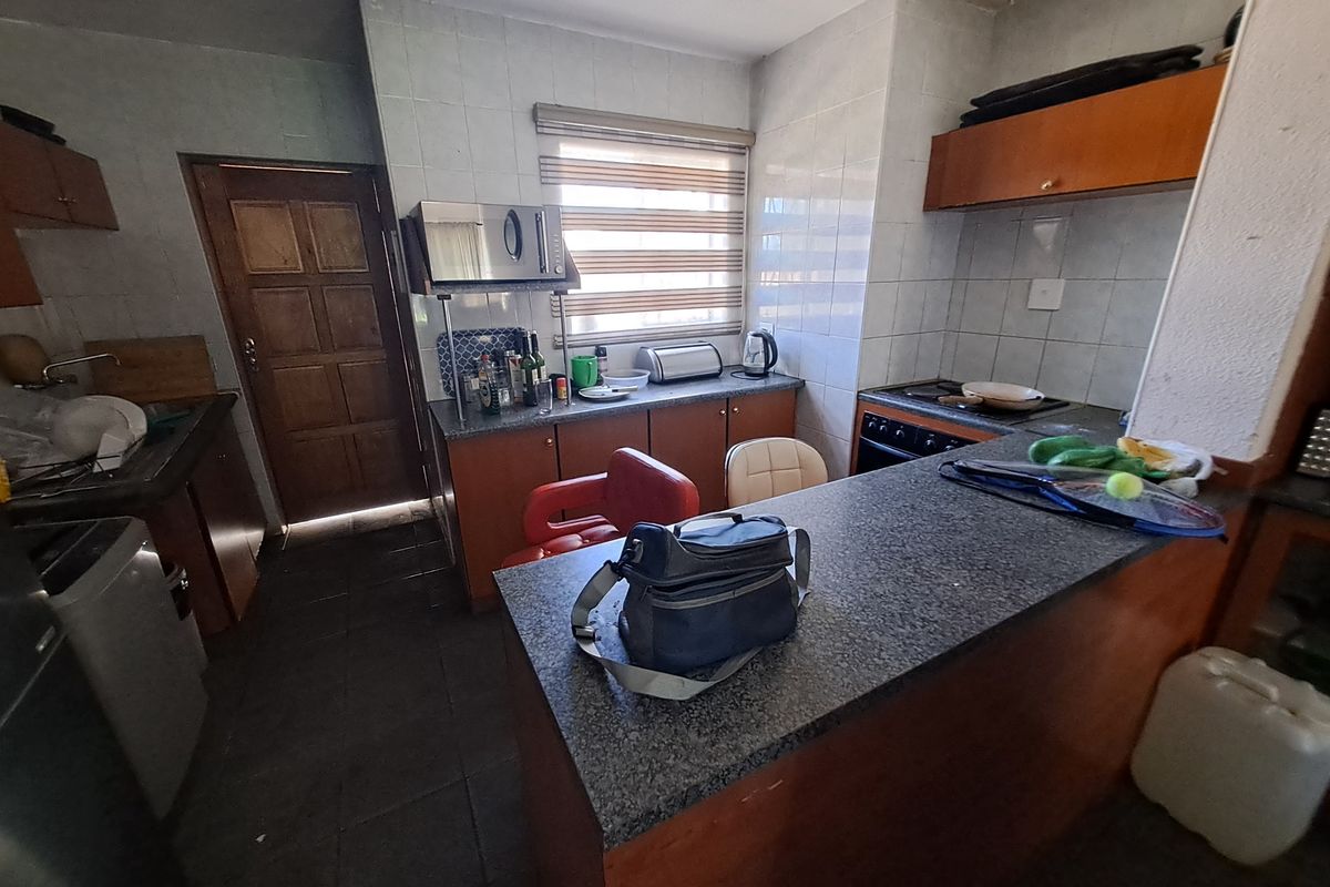 A functional kitchen featuring built-in cabinetry, granite countertops, a built-in oven, and a tiled splashback, offering a practical layout for daily meal preparation.