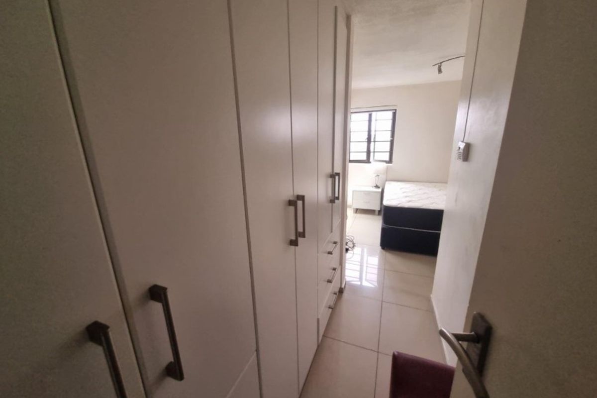 Bedroom featuring built-in cupboards and tiled flooring, providing functional storage and a clean, neutral aesthetic.