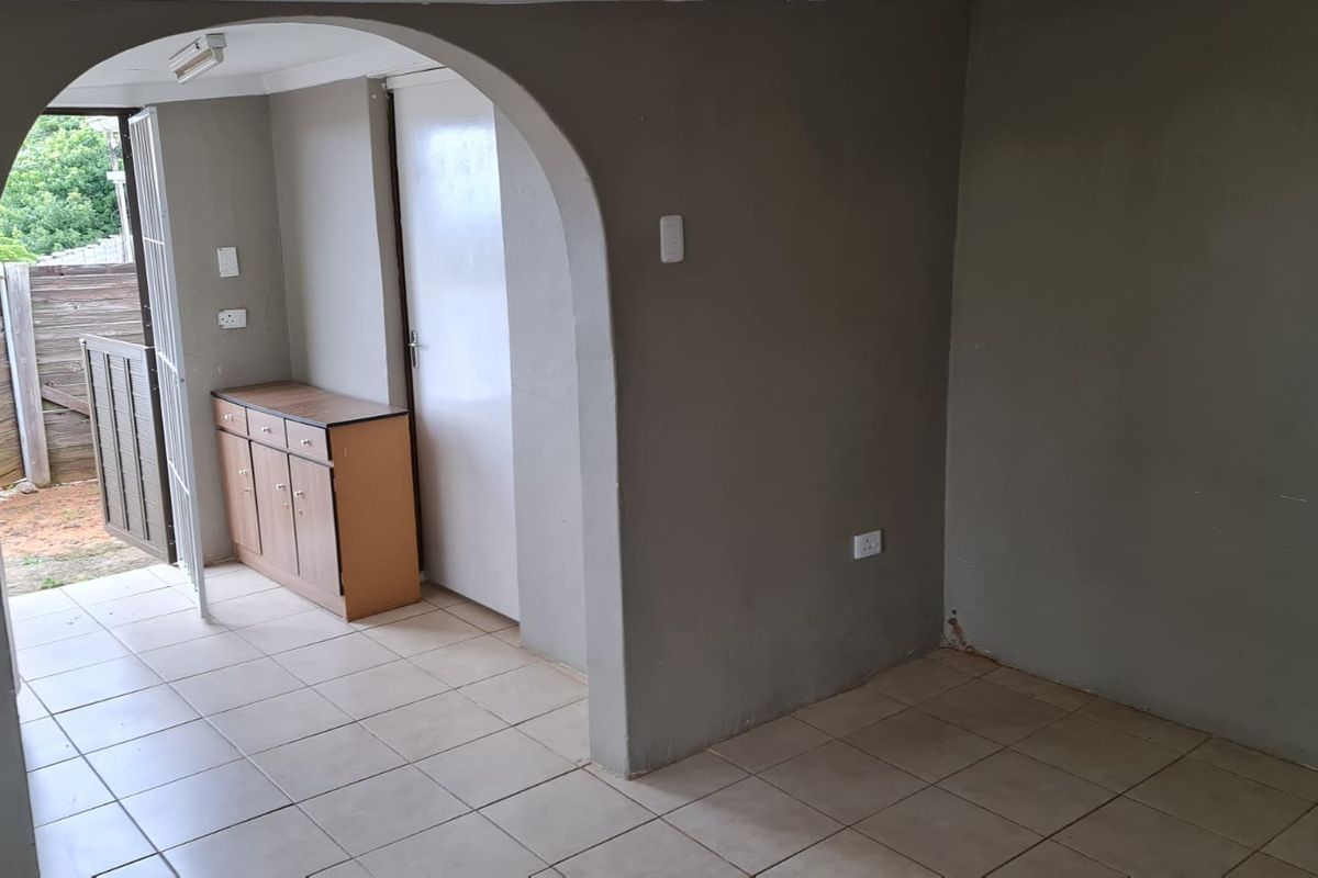 An empty living area featuring tiled flooring and a distinctive arched doorway leading to an exterior access point.
