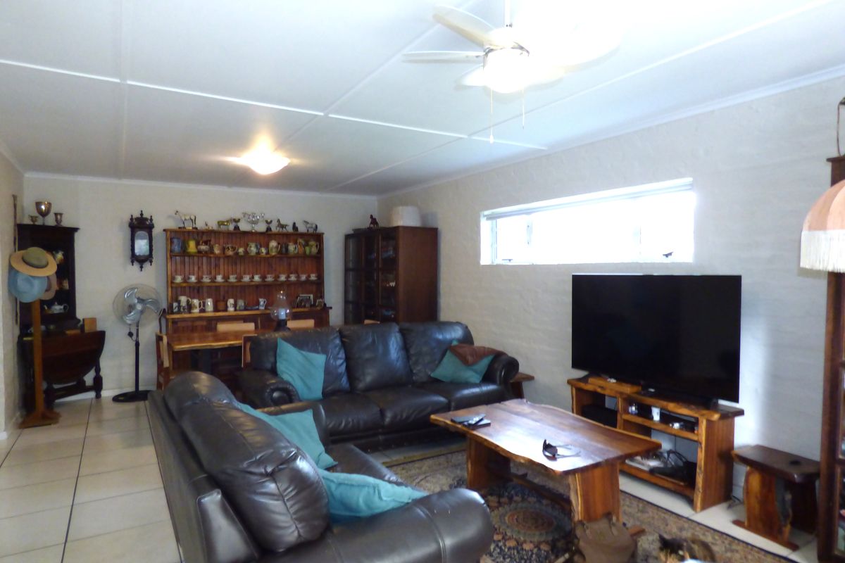 A spacious living room featuring tiled flooring, a ceiling fan, and textured walls, offering a comfortable and functional layout for relaxation.
