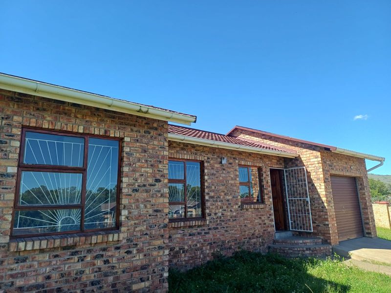 A single-story face brick house featuring a tiled roof, integrated garage, and secure metal window and door grilles.
