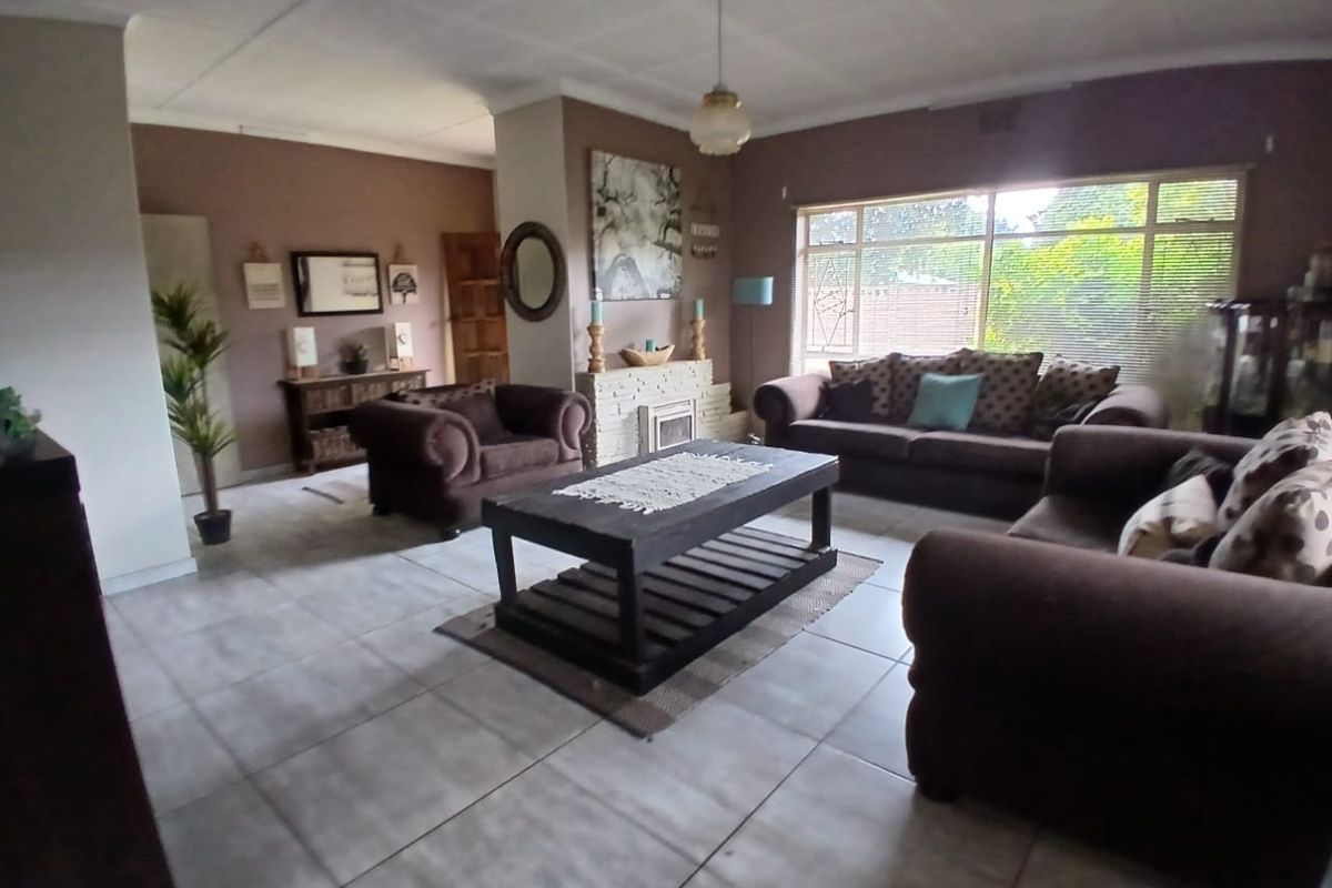 Spacious living room featuring tiled flooring, a central fireplace, and large windows providing natural light.