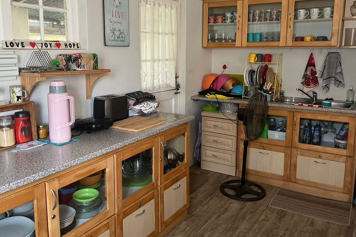 A functional kitchen featuring wooden cabinetry, laminate countertops, and a stainless steel sink, offering a practical layout with ample storage space.