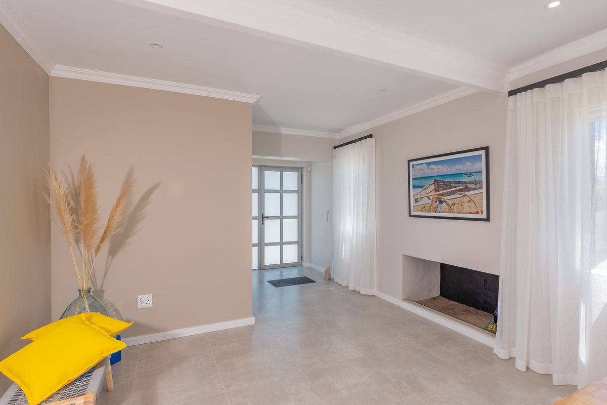 A bright living room featuring neutral walls, tiled flooring, crown molding, and a built-in fireplace, leading to a glass-panelled entrance door.